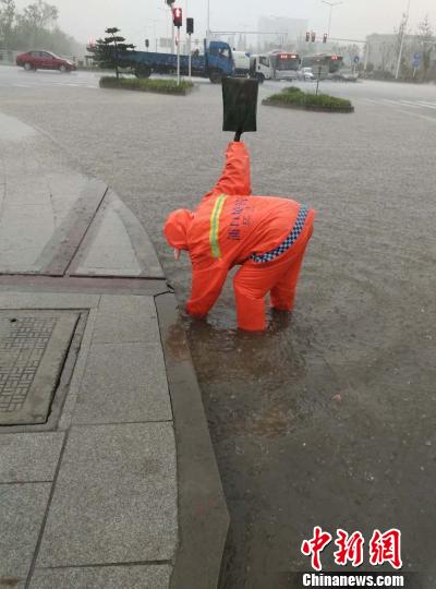 环卫工人在雨中忙着去除排水口里的落叶和堵塞物。　城管供图　摄