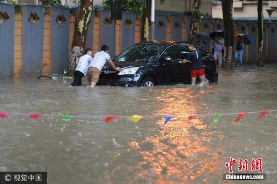 图为6月10日，南京市雨花台区，几个男子推着抛锚的汽车。来源：视觉中国