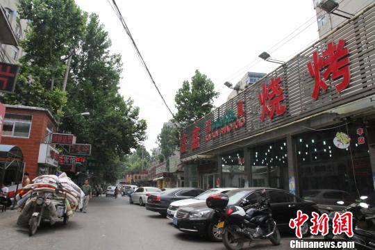 饮虎池街街道南侧的烧烤店铺林立，等待拆迁整治。　赵晓 摄