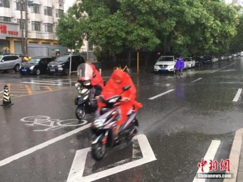 图为北京阜成路，市民雨中骑行。 记者 富宇 摄